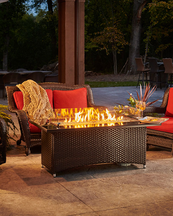 Montego Fire Pit table at night with a lit fire building a warm ambiance