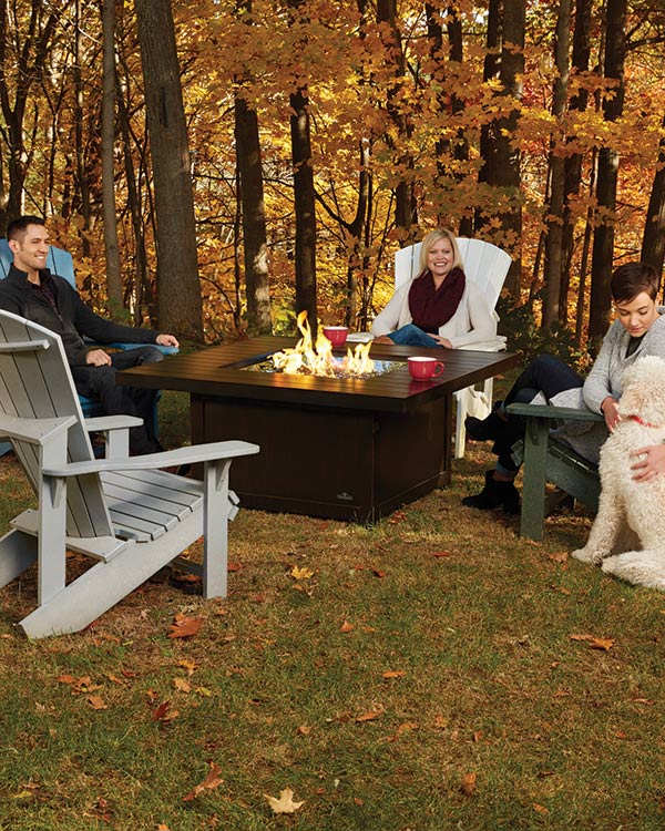 Napoleon St. Tropez Fire Table in a yard during the fall with family sitting around smiling